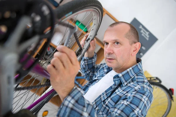 Mężczyzna w średnim wieku naprawy rowerów biegów w swoim warsztacie — Zdjęcie stockowe