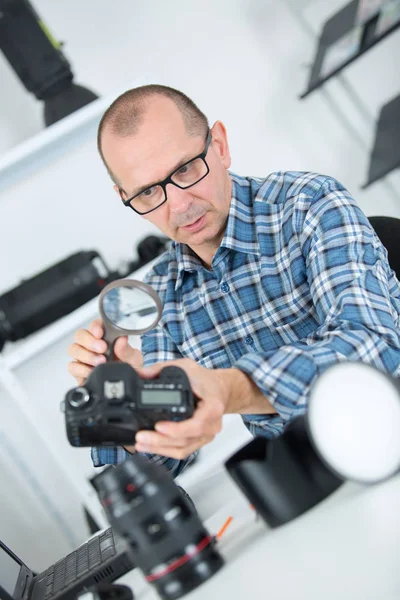 Ingeniero técnico comprobando sensor dslr con lupa — Foto de Stock