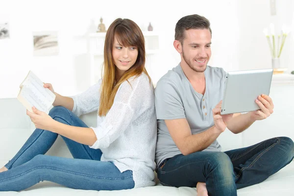 Couple sur canapé avec tablette numérique et livre — Photo