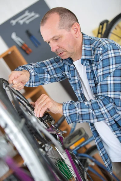 Ein Mann repariert Fahrrad in seiner Werkstatt — Stockfoto