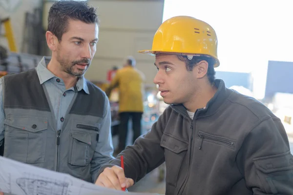 Mannelijke werknemer iets tonen aan mede-werker op zijn papieren notitieblok — Stockfoto