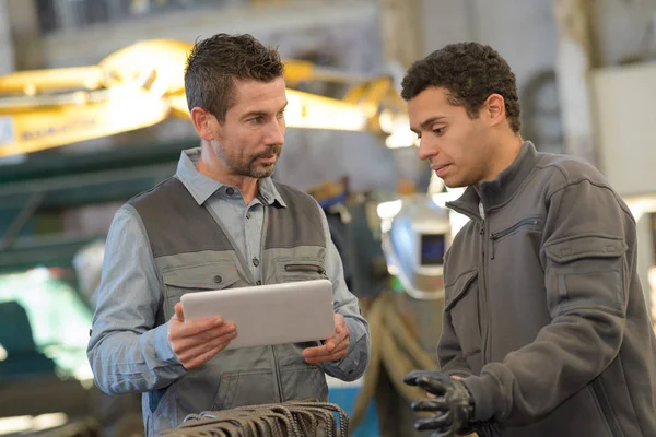 Pekerja pabrik berdiskusi dengan tablet digital di gudang — Stok Foto
