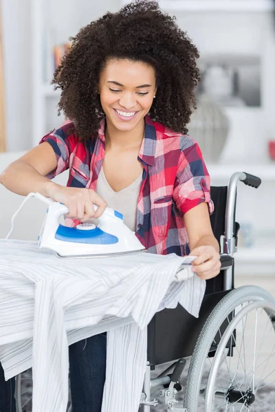 Donna sulla sedia a rotelle durante la stiratura a casa — Foto Stock