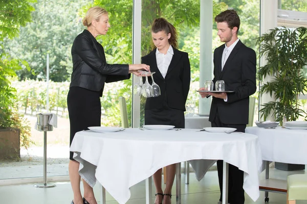 Dame lehrt Hotelstudenten, wie man einen Tisch richtig deckt — Stockfoto