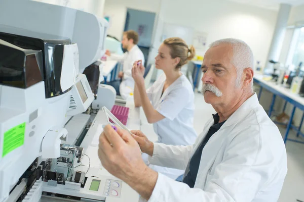 Scienziato senior che guarda lo scivolo al laboratorio — Foto Stock