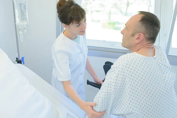 Sjuksköterska som håller patienter i handen på en sjukhussäng — Stockfoto