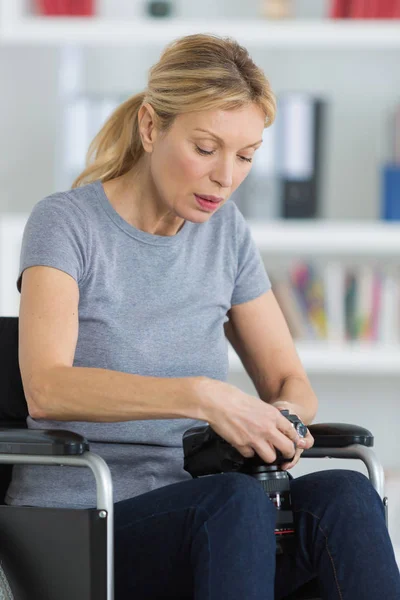 Donna di mezza età su una sedia a rotelle cercando immagine nella fotocamera — Foto Stock
