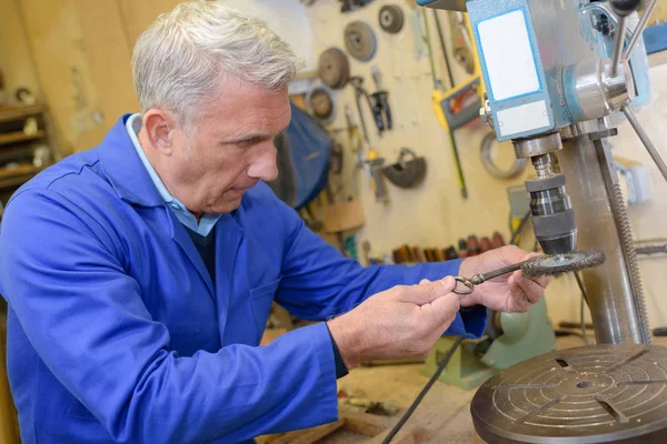 Senior-Schlosser bohrt Schlüssel an seinem Arbeitsplatz ein — Stockfoto