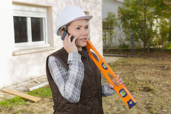 female construction worker with level at construction site