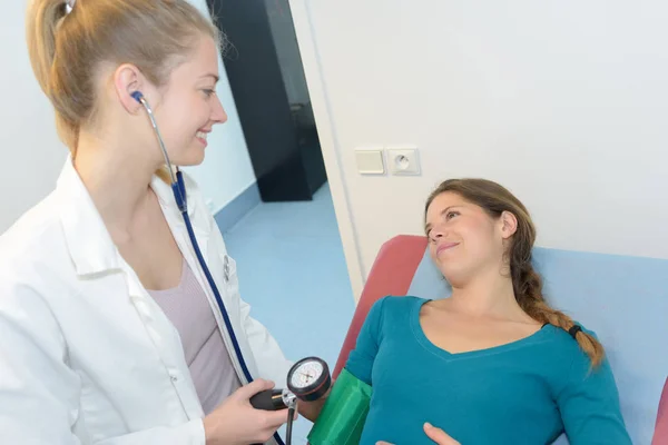 Läkare kontrollerar blodtryck av en kvinnlig patient — Stockfoto
