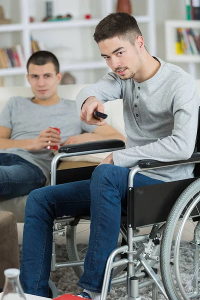 Behinderter junger Mann schaut mit Freund fern — Stockfoto