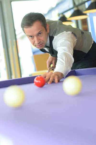 Jeune homme confiant jouant au billard et regardant concentré — Photo