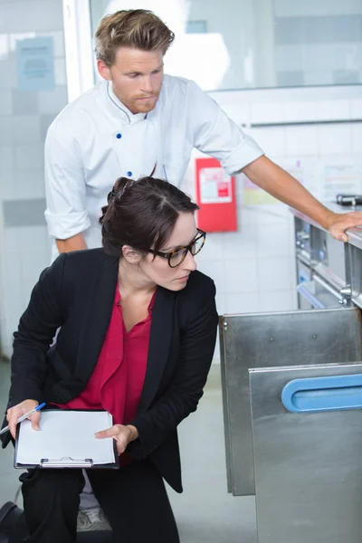 Ispettore che esamina le provviste alimentari nella cucina del ristorante accompagnato dallo chef — Foto Stock