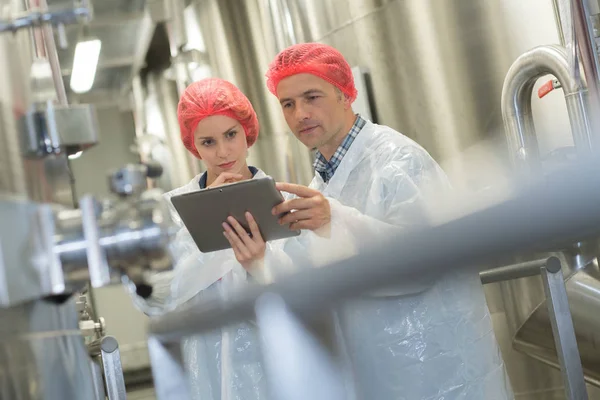 Man wijst op iets naar zijn collega in de fabriek — Stockfoto