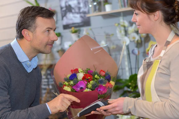 Florist serverar manliga kund när du köper blommor i butik — Stockfoto