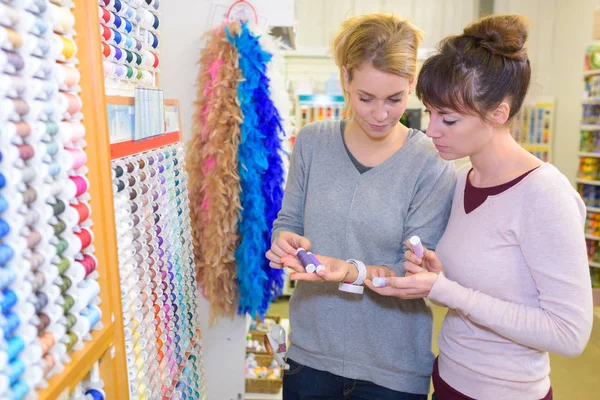Mujeres sosteniendo carrete de costura en el departamento de costura en la tienda — Foto de Stock