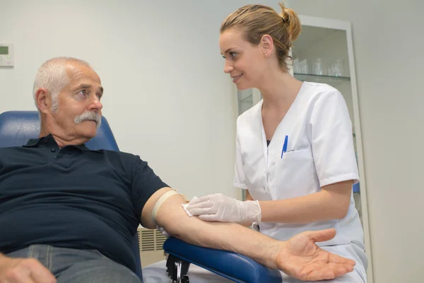Молодая женщина делает анализ крови для пожилого мужчины с диабетом — стоковое фото