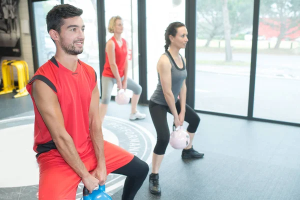 Três atletas musculares prestes a levantar um sino de chaleira — Fotografia de Stock