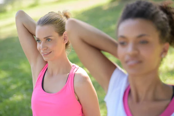 Vänner stretching tillsammans i en park — Stockfoto