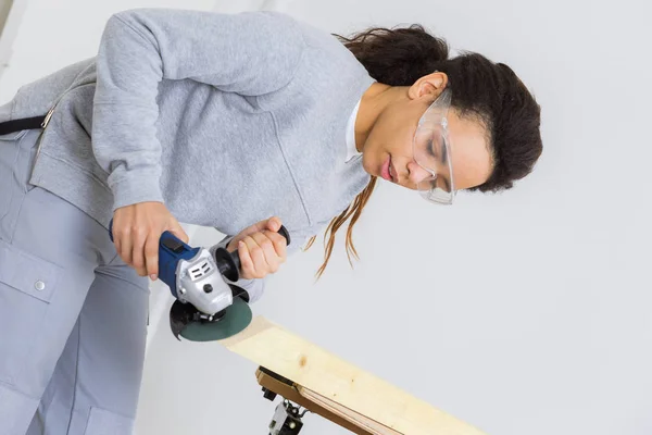 Joven trabajadora de la madera moliendo madera en taller —  Fotos de Stock