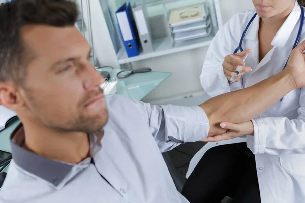 Médico do sexo masculino a injectar um braço de doentes no consultório médico — Fotografia de Stock