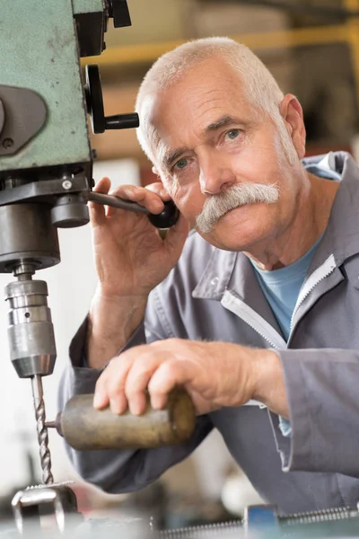 Senior-Schreiner bohrt Loch in Metallplanke in seiner Werkstatt — Stockfoto