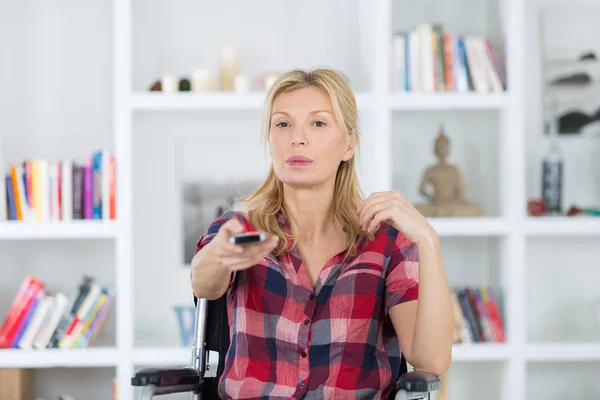 Frau mittleren Alters im Rollstuhl sieht Film zu Hause im Fernsehen — Stockfoto