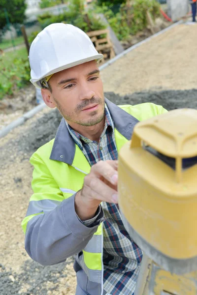 Male construction builder taking measurements at construction site — Stock Photo, Image