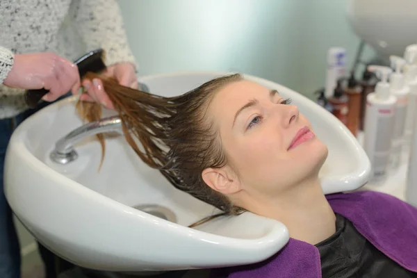 Piękna kobieta jest coraz hairwash przez salon fryzjerski — Zdjęcie stockowe