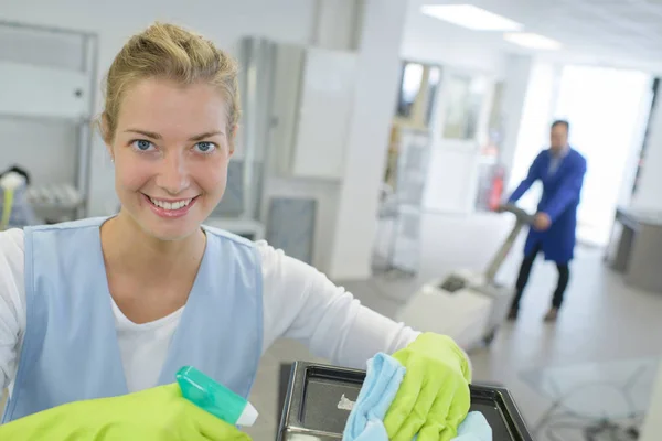 Jonge vrouwelijke reiniger in schort met leveringen werken binnenshuis — Stockfoto
