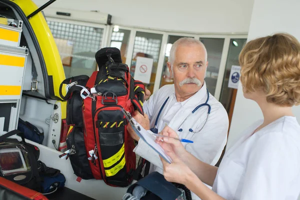 Tripulación de ambulancia masculina y femenina comprobando su equipo antes de la intervención —  Fotos de Stock