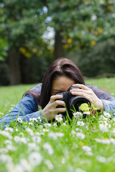 Giovane donna utilizzando dslr posa all'aperto su erba — Foto Stock