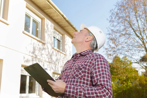 Mannelijke toezichthouder Klembord op bouwplaats op zonnige dag lezen — Stockfoto