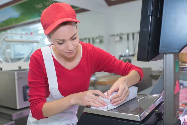 Porträtt av vackra slaktare packning kött i papper på shop — Stockfoto