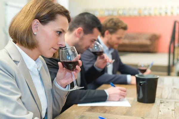 Tres jóvenes tomando notas mientras hacen cata de vinos — Foto de Stock