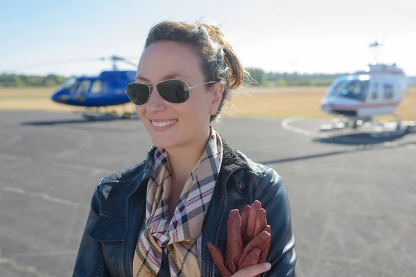 Young woman helicopter pilot posing in front of helicopters — Stock Photo, Image