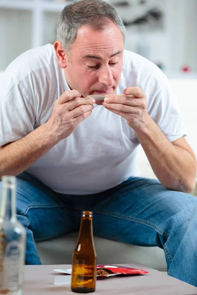 Mellersta åldern man rullar en cigarett — Stockfoto