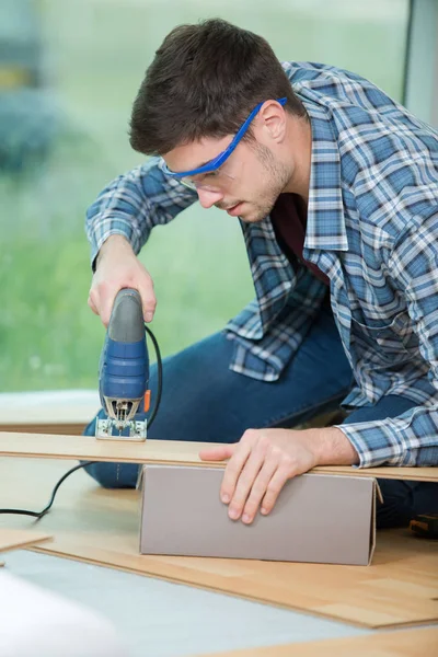 Arpenter with electric drill drilling wood plank at workshop — Stock Photo, Image