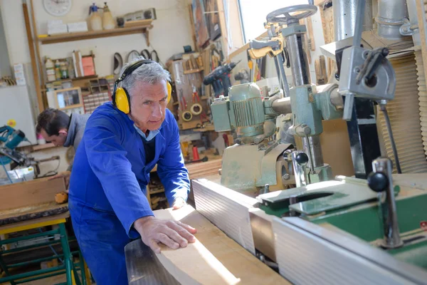 Alter Tischler sägt Bretter in seiner Werkstatt — Stockfoto