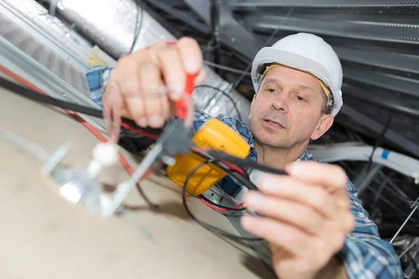 Eletricista reparar fiação dentro do teto do escritório — Fotografia de Stock