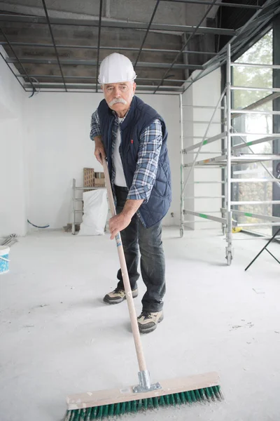 Male worker cleaning warehouse with mop — Stock Photo, Image