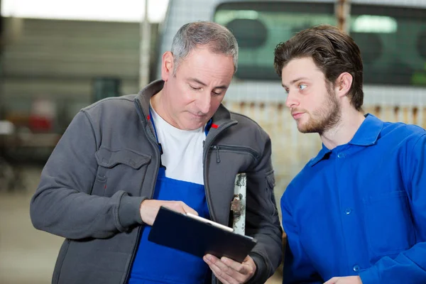 Mechaniker hilft Lehrling beim Reparieren des Motors — Stockfoto