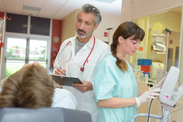 Médico e enfermeiro com computador tablet pc visitando paciente sênior — Fotografia de Stock