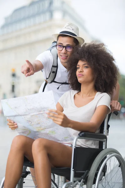 Молодая пара, приезжающая в город - женщина на инвалидной коляске — стоковое фото