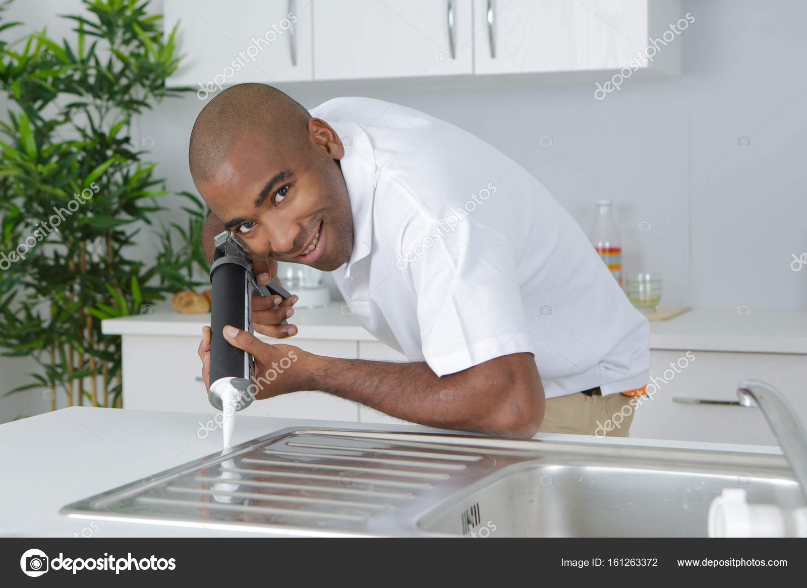 Plumber Putting A Silicone Sealant To Installing Kitchen Sink
