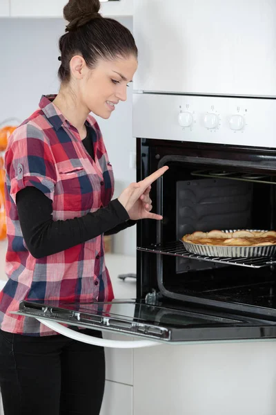 Mulher colocando um bolo no forno — Fotografia de Stock