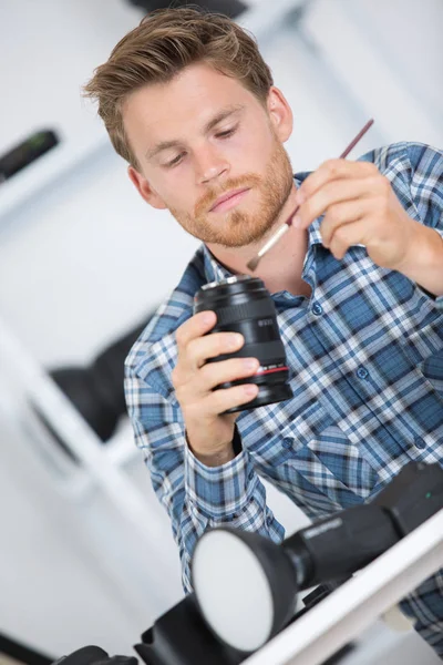 Joven fotógrafo limpia la lente para obtener imágenes claras —  Fotos de Stock