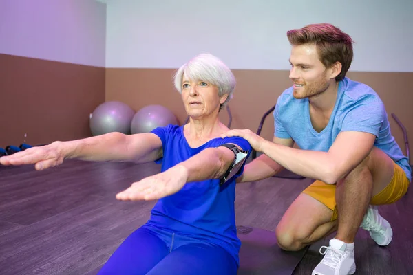 Fitness-instruktör hjälper senior kvinna med hållning — Stockfoto