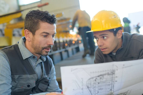 Männlicher Vorgesetzter diskutiert mit Arbeitern über Baupläne in der Industrie — Stockfoto