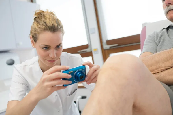 Kvinnliga läkare tar en bild av en skadade knä — Stockfoto